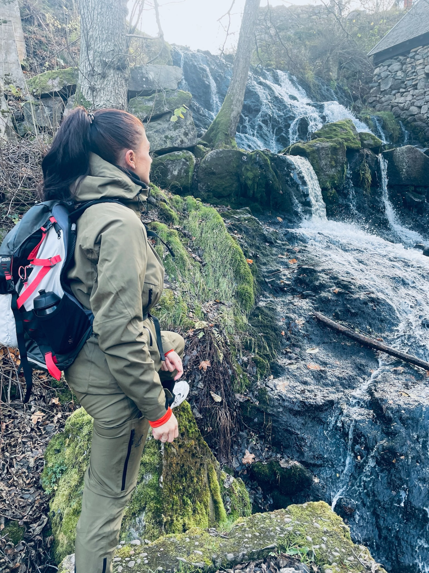 Debbie in outdoor gear with a running vest looking at a waterfall