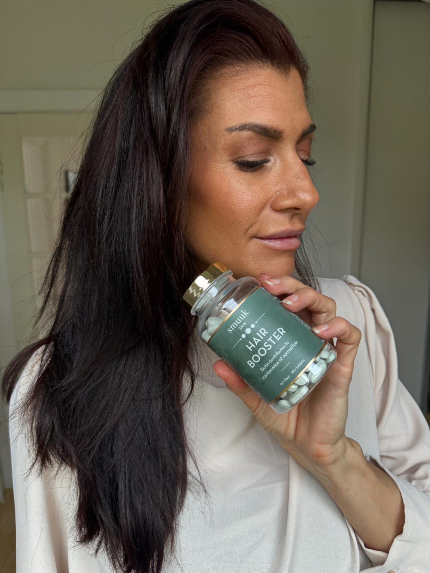 Debbie holding a hair booster supplement bottle